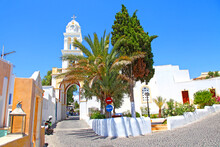 A Narrow Cobblestone Street With An Arched Bell Tower In The Traditional Village Of Megalochori In Santorini, Greece. 