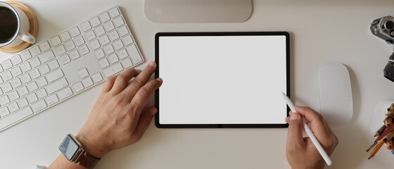 Businessman using blank screen tablet with stylus on white office desk with computer device and other supplies