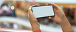 © bongkarn - A girl holding horizontal mock-up smartphone while standing at balcony in shopping mall