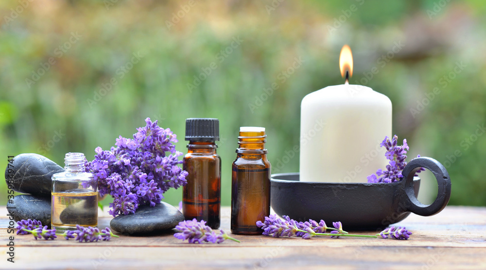bottles of essential oil among lavender flower arranged on a wooden ...