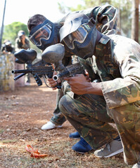 Wall Mural - Paintball players aiming and shooting with guns at opposing team outdoors