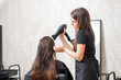 Master hairdresser blow dry client of young woman in spa beauty salon