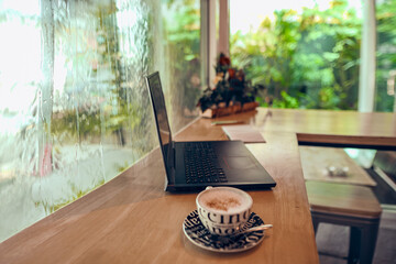   laptop and cup of coffee on a table in a cafe               