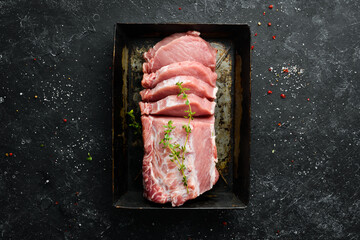 Raw pork fillet with spices on a black stone background. Meat. Top view. Rustic style.