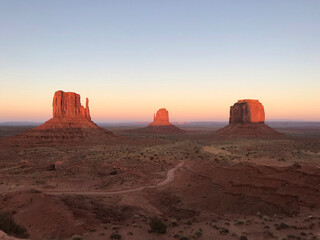 Amazing view of Monument Valley with red desert and blue sky and clouds in the morning. Monument Valley in Arizona with West Mitten Butte, East Mitten Butte, and Merrick Butte.	