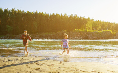 boys running on the beach of river