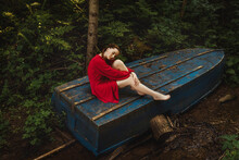 The Young Woman In Red Dress On Blue Boat In Forest.