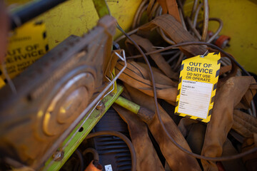 Safety workplaces yellow out of service tag on faulty damage defect on 2 ton green lifting sling at construction site Perth, Australia