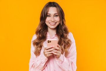 Wall Mural - Image of beautiful pleased woman smiling and using mobile phone