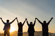 Group Of Happy Friends Are Having Fun With Raised Arms Together In Front Of Mountain And Enjoy Sunrise Sunset Showing Unity And Teamwork. Friendship Happiness Leisure Partnership Team Concept.