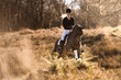 Dressurreiterin galoppiert lachend mit ihrem Pony durch die Heide