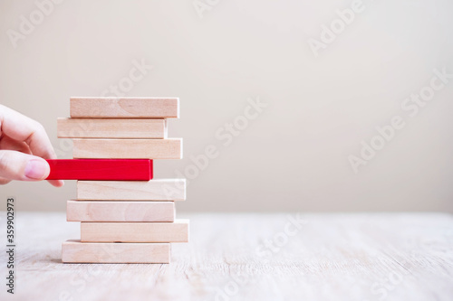 Fotografía Businessman hand placing or pulling red wooden block on the tower