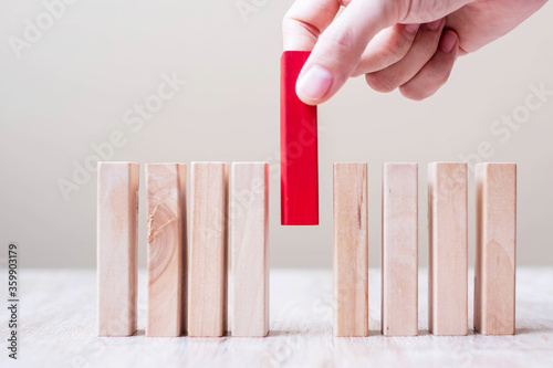 Fotomural Businessman hand placing or pulling Red wooden block on table