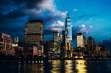 Scenery view of Lower Manhattan skyline at evening with city lights reflected in Hudson river. Beautiful New York cityscape view. Contemporary metropolis city in need of a huge amount of electricity