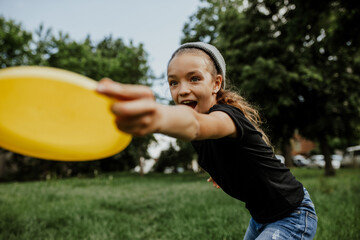 Little girl playing frisbee in the park. Summer time