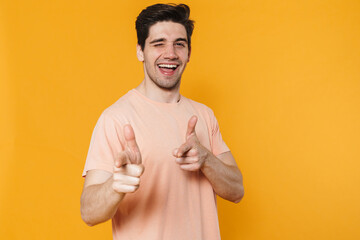 Wall Mural - Photo of happy handsome man pointing fingers at camera and winking