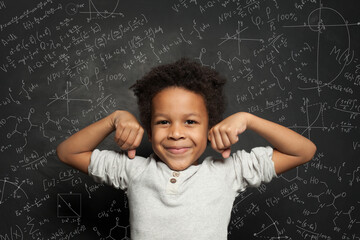 Wall Mural - Cute black child student boy on chalkboard background with science formulas