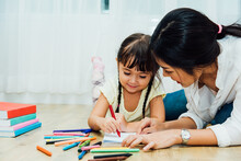 Happy Asian Child Kid Daughter Kindergarten And Young Beautiful Parent Mother Teaching Drawing And Play Color Together At Interior Room Home, Family Day And Back To School Concept