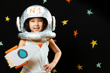 portrait of a cute little aisan girl, space at home, dreaming and playing astronaut. funny family mo