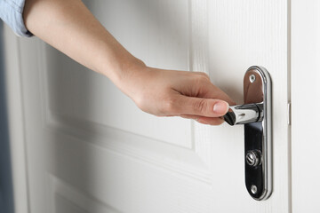 Woman opening white wooden door indoors, closeup