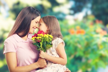 Wall Mural - Mother and daughter with bouquet of flowers on blurred background.