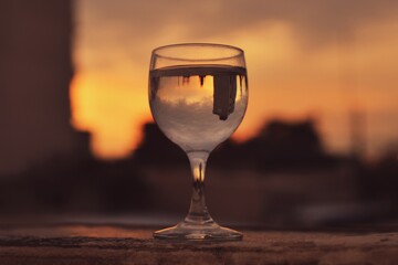 Close up of glass with water on terrace at sunrise with reflected building