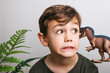 © Westend61 - Portrait of little boy with toy dinosaur pulling funny face