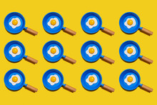 Pattern Of Rows Of Fried Eggs On Blue Pans Against Yellow Background