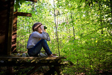 Girl Using Binoculars In Forest