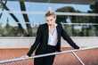 © Westend61 - Portrait of young businesswoman wearing black pantsuit standing in front of an office building