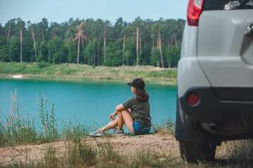 Wall Mural - woman sitting on the edge enjoying view of the lake