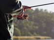 © Gary Radler/Austockphoto - Close up of Man winding Fishing Reel while Holding a Rod