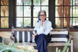 © Trinette Reed/Stocksy - Portrait of beautiful and stylish mature woman interior designer with grey hair sitting on front porch