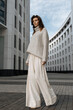 © Ivan Ozerov/Stocksy - girl in a gray sweater and wide white pants against the backdrop of modern architecture