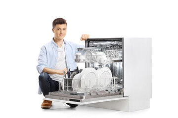 Wall Mural - Casual young man next to an open dishwasher