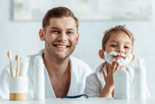 Selective Focus Of Cheerful Man Looking At Camera Near Adorable Son With Shaving Foam On Face