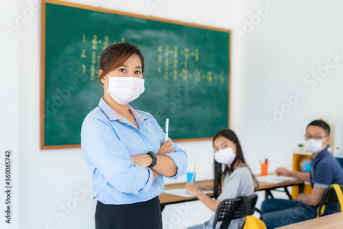 Asian woman teacher wearing masks to prevent the outbreak of Covid 19 in classroom with student while back to school reopen their school, New normal for education concept..