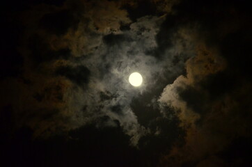 Beautiful vivid cloudscape. Night sky with a bright full moon and cloudy, serenity blue nature background. Outdoor at nighttime with moonlight.