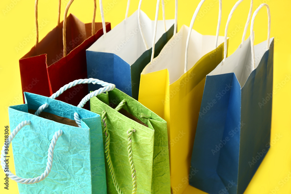 Paper shopping bags on color background