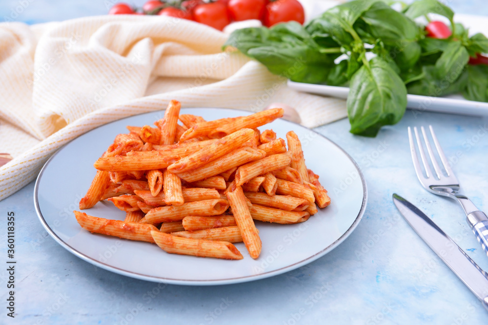 Plate with tasty pasta and tomato sauce on color background