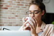 © Drobot Dean - Image of woman working with laptop and drinking coffee while sitting