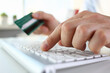 © H_Ko - Close up of male hands typing on white keyboard and holding credit card
