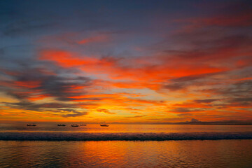 Wall Mural - Fishermen boats silhouettes in tropical fiery sunset light at Kuta beach, Bali island, Indonesia 