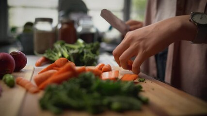 Wall Mural - Close up of a woman slicing carrot with kitchen knife on cutting board and preparing salad in the kitchen