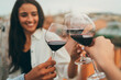 Group of millennial friends toasting wine at rooftop party, Young people laughing enjoying drinks at rooftop bar, Positive hipsters making cheers with wine glasses, Friends celebrating and having fun