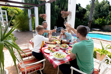 Wall Mural - Caucasian family sitting at table during a family lunch in the garden