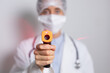 © wavebreak3 - Healthcare worker holding gun thermometer and wearing coronavirus Covid19 mask