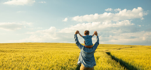 father and son in wheat field, child sitting on his fathers shoulders