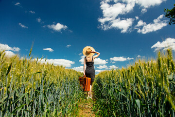 Sticker - Beautiful blonde girl with suitcase in wheat field in sunny day