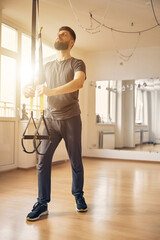 Wall Mural - Coach adjusting the straps of suspension trainer